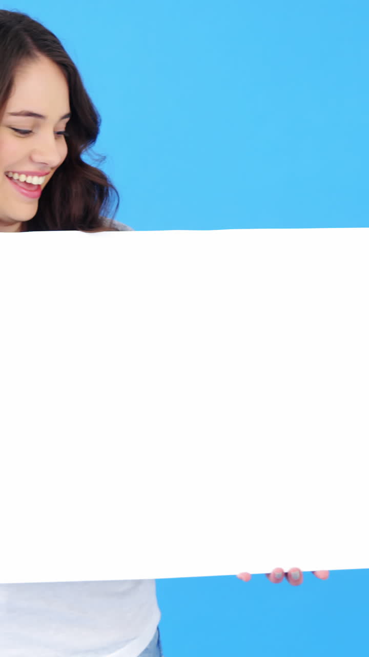hermosa mujer sosteniendo un cartel en blanco sobre un fondo azul