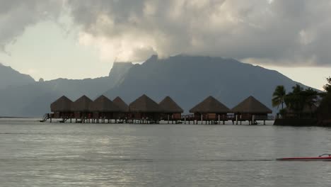 man canoeing on paradise scenery. sea cottage houses on sea, mountains and some clouds in background.