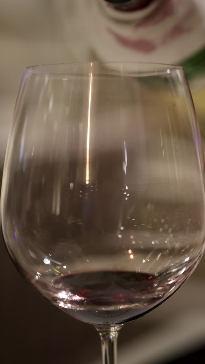 En sekvens der viser rødvin hældes i et glas, hvilket fremhæver hældningens elegance og præcision