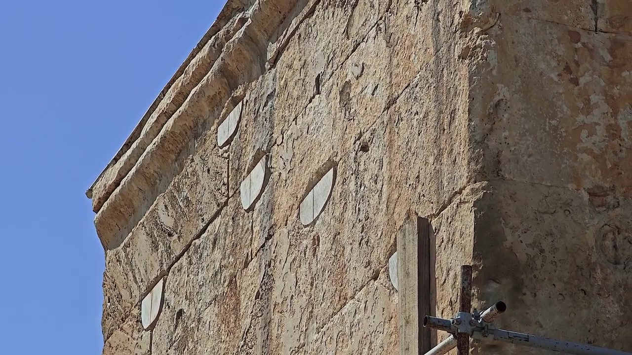 Antico muro di pietra di un edificio storico sotto un cielo azzurro limpido