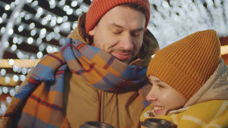 Portrait-of-Loving-Couple-with-Coffee-on-Christmas-Lights