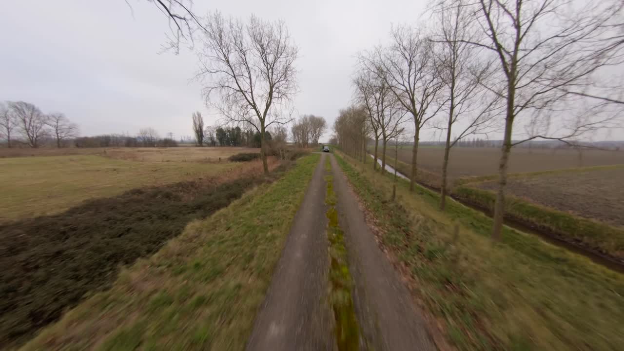 Fast aerial shot of a road on a dyke surrounded by trees