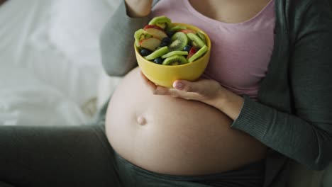 detail video of pregnant woman eating a bowl of fruits