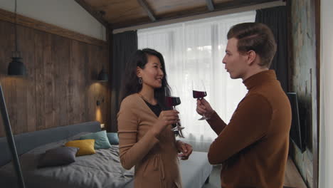 una pareja celebrando con vino en un dormitorio acogedor