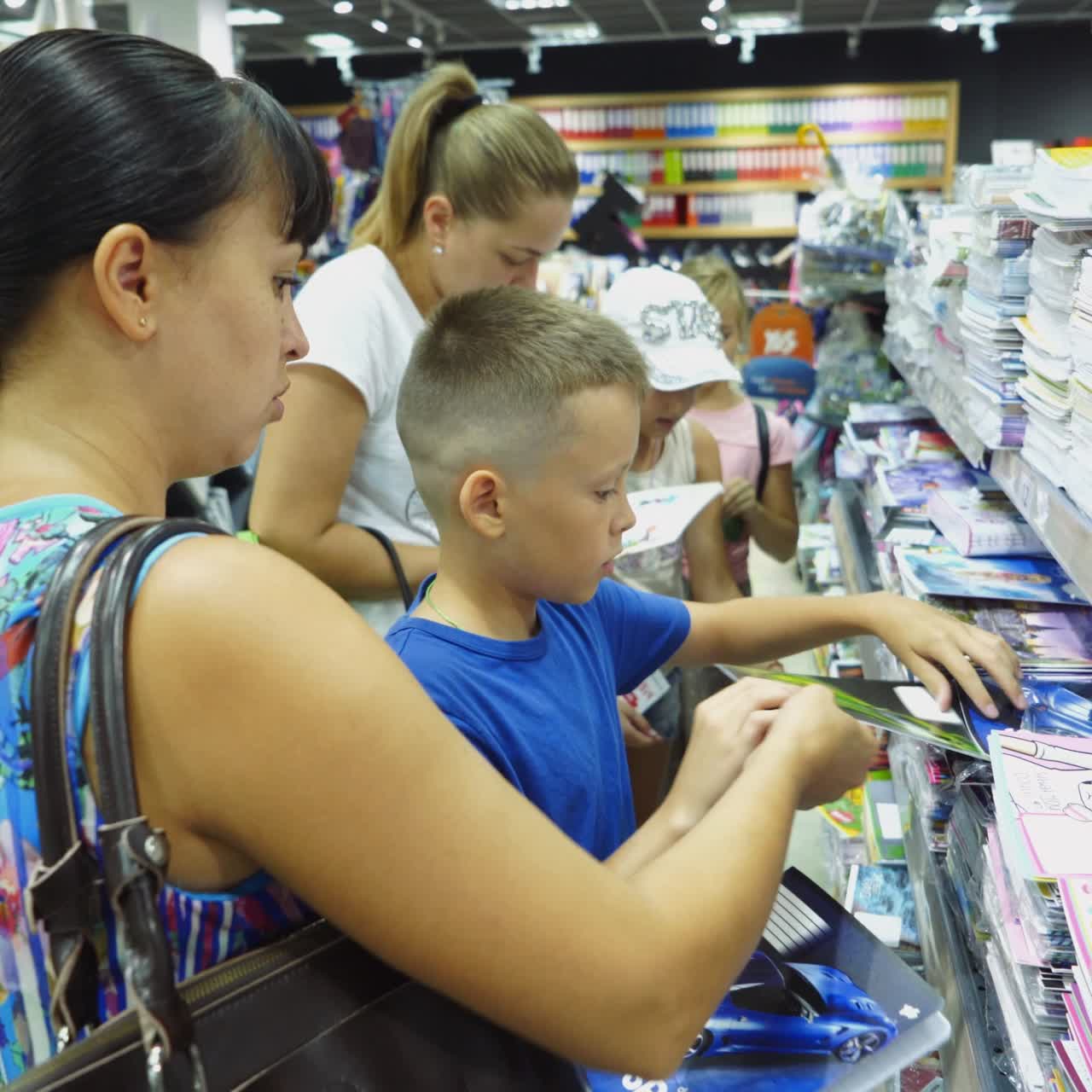 VINNITSA, UKRAINE - AUGUST 20, 2018: Back to school concept. Young mother and little boy buying school supplies in store.