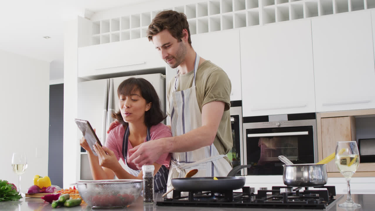 video de una pareja feliz y diversa preparando comida juntos con una tableta