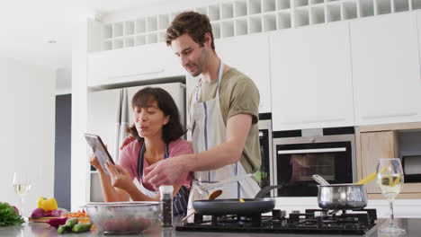 video of happy diverse couple preparing meal together with tablet