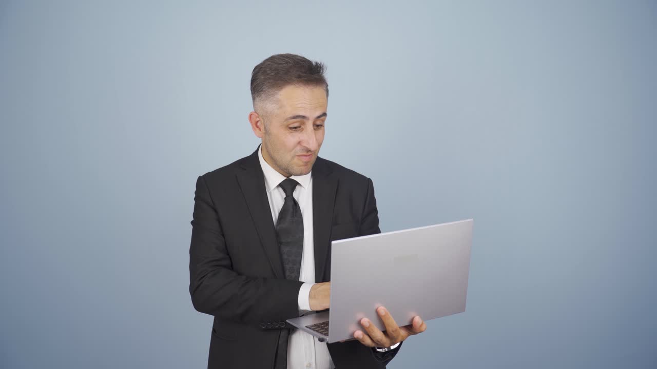 el hombre de negocios satisfecho mira la computadora portátil y aprueba.