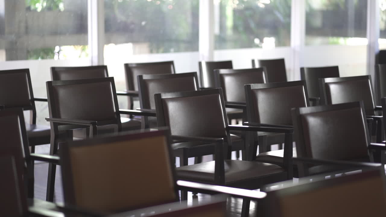 Rows of empty chairs in a well-lit indoor showroom with large windows and soft natural light.