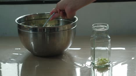 transferring shredded cabbage to mason jar for sauerkraut fermentation