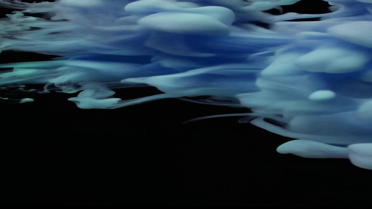 Inchiostro blu che si diffonde nell'acqua su sfondo nero