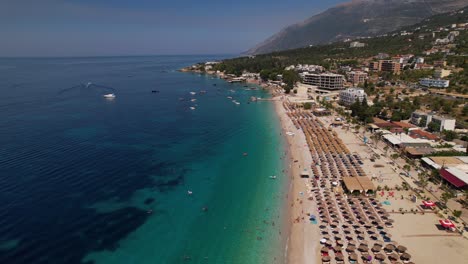 Großer-Strand-Von-Dhermi-Mit-Sonnenschirmen,-Die-Von-Sauberem,-Türkisfarbenem-Wasser-Des-Mittelmeers-Gewaschen-Werden