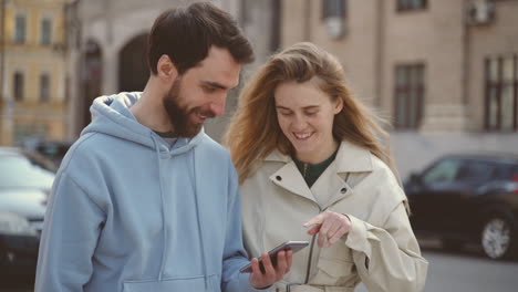 una pareja joven viendo algo gracioso en la pantalla del celular