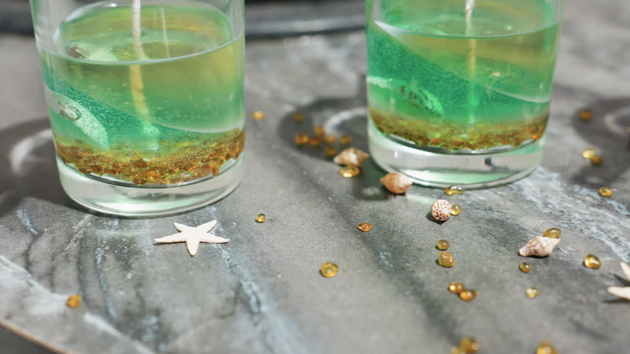 Round view of candle mold with layered green and golden wax, decorative materials on chefs table capturing warm glow, wicks secured by wooden sticks for creative candle crafting in cozy environment