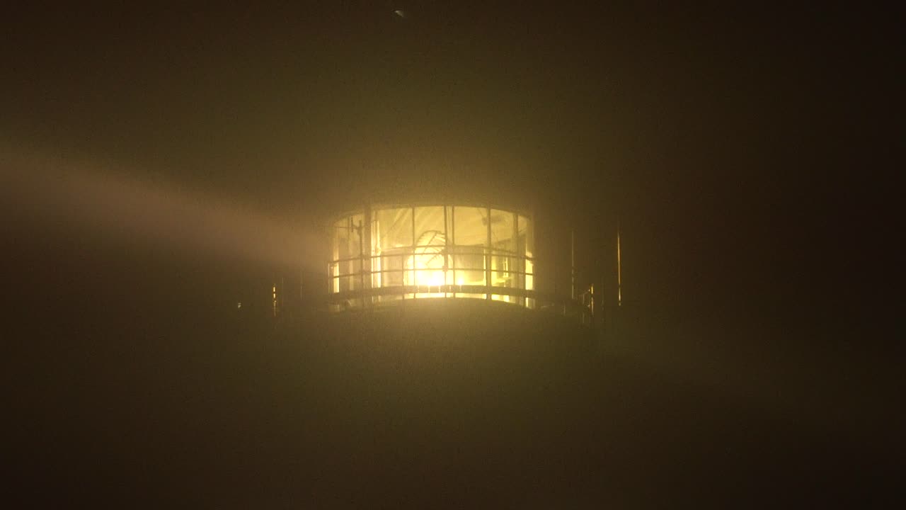 짙은 안개를 관통하는 광선으로 등대 램프를 닫습니다.