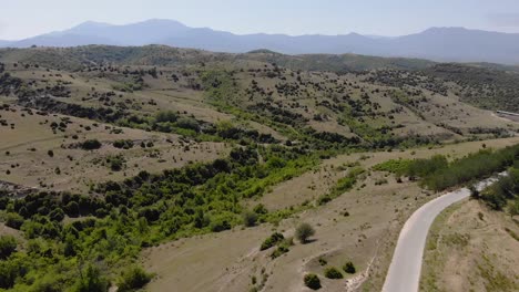 Flying-over-empty-fields-in-the-mountains-separated-by-an-empty-road