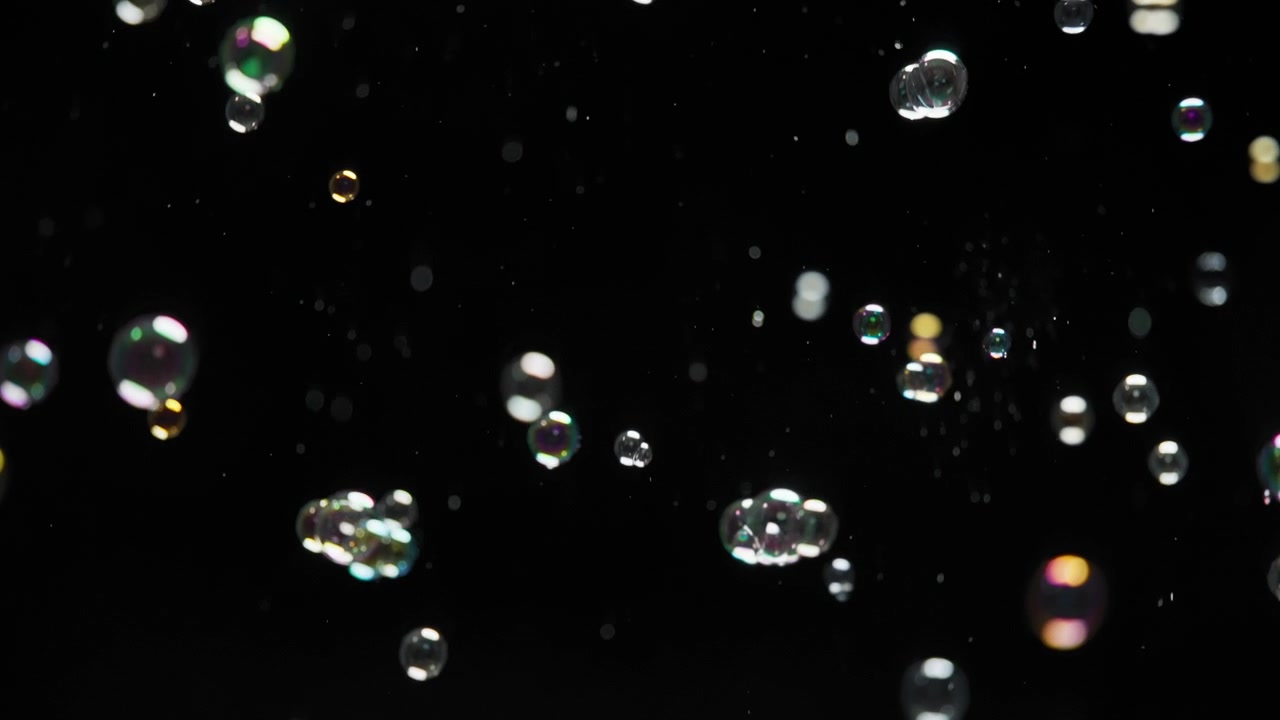 Overlejring af sæbebobler, der flyver på sort baggrund. Slowmotion.