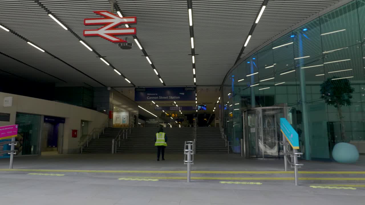 Lone railway key worker entering an empty Cannon Street Station, central London, UK