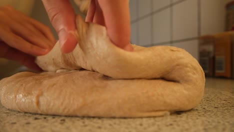 Shaping-a-homemade-loaf-of-sourdough-bread-dough-in-the-kitchen