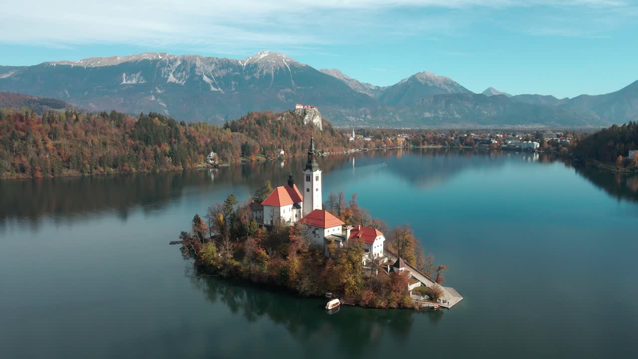 Kalme weerspiegeling van water op het meer van Bled, terwijl de drone een luchtfoto toont van het eiland en de kerk van Bled met de berg Stol op de achtergrond