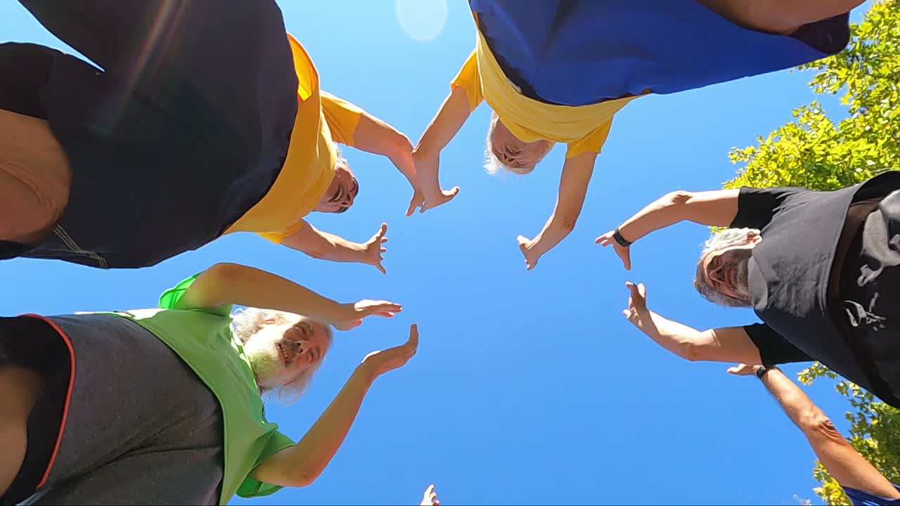 둥글게 서 있는 한 시니어 축구팀의 아래에서 바라보고, 훌쩍거리고, 팔을 들고, 손뼉을 친다