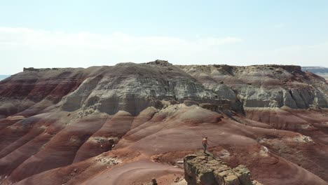 Orbit-Aerial-View-of-Lonely-Shirtless-Man-Standing-on-Top-of-The-Hill-in-Desert-Landscape-of-Utah,-USA