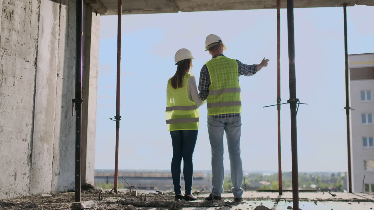 pareja de ingenieros o técnicos hombre y mujer con casco de seguridad sosteniendo un teléfono móvil de radio planeando sobre el plan de construcción para saludar el inicio del proyecto en el sitio de construcción concepto de la industria de la construcción