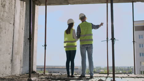 Pareja-De-Ingenieros-O-Técnicos,-Hombre-Y-Mujer-Con-Casco-De-Seguridad,-Sosteniendo-Un-Teléfono-De-Radio-Móvil,-Planificando-El-Plan-De-Construcción-Para-Saludar-El-Inicio-Del-Proyecto-En-El-Concepto-De-La-Industria-De-La-Construcción-En-El-Sitio-De-Construcción.