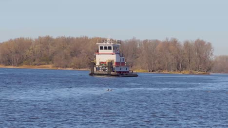 a wide-angle of a barge with no cargo is moving down the mississippi river