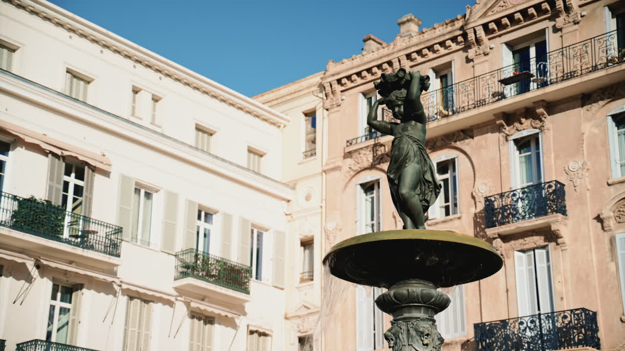 Primo piano di una statua di fontana in bronzo con acqua che scorre, circondata dall'architettura classica in Place du General de Gaulle