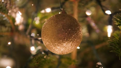 Bola-De-Adorno-De-Oro-En-El-árbol-De-Navidad-Con-Luces-Bokeh-En-4k