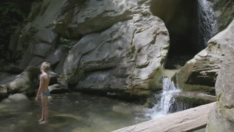 boy exploring a waterfall in a rocky canyon