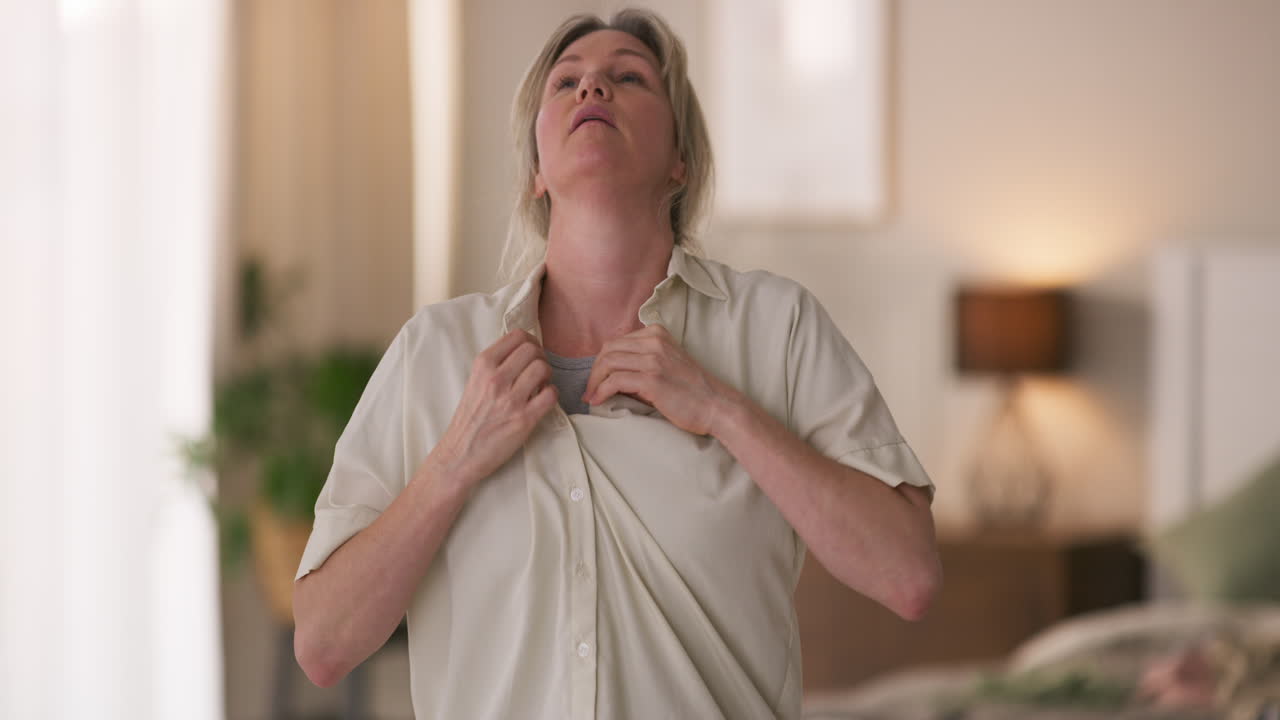 Woman buttoning shirt in bedroom