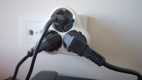 primer plano de una tira de alimentación blanca con múltiples enchufes y cables