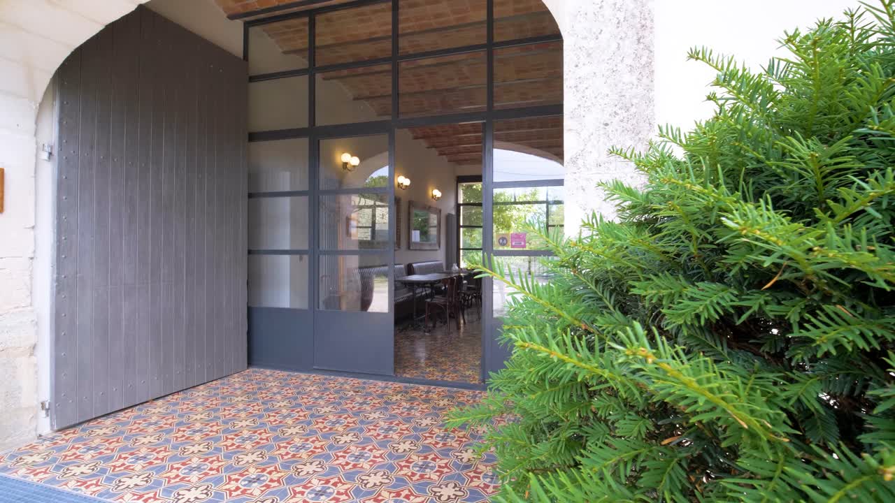Slow revealing shot of a villa entrance opening from behind garden plants