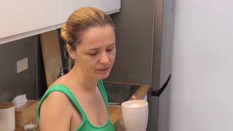 mujer disfrutando de café y una galleta en la cocina