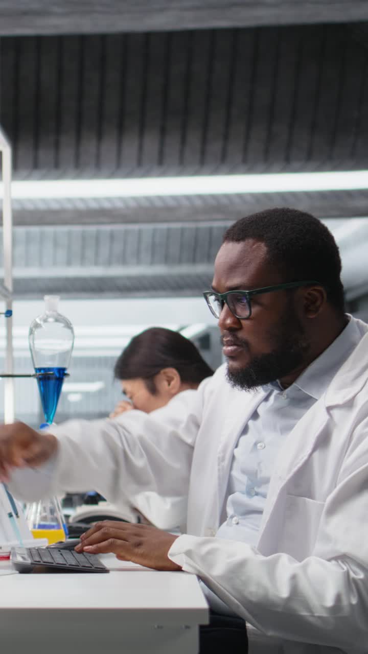 Vertical video Quality control analyst in laboratory analyzing solution at workstation using PC