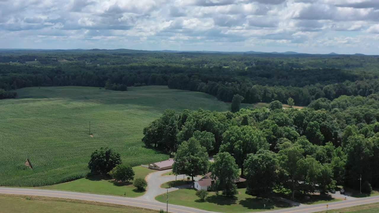 Drone footage flying over a farm house and cornfield in the country