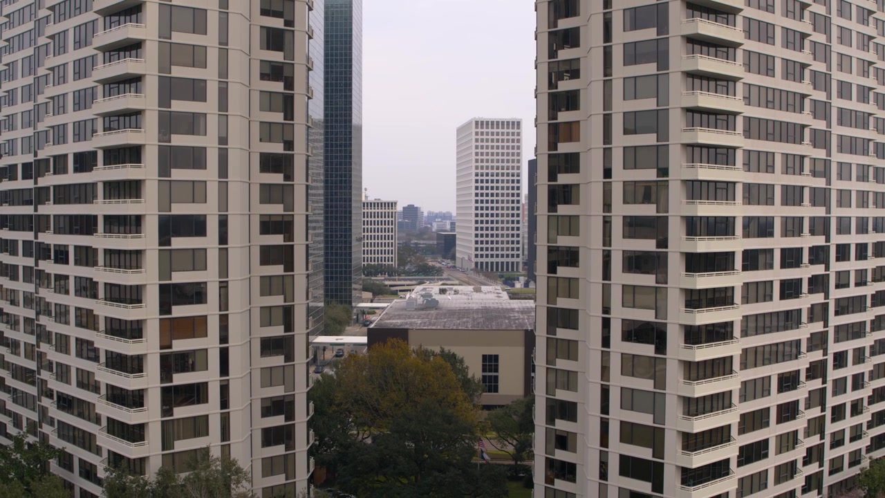 Plano de drone em recuo subindo acima de condomínios de luxo para revelar o horizonte completo de Houston. Imagens aéreas cinematográficas perfeitas para