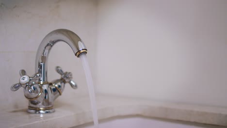 Female-hand-turning-water-tap-for-pouring-water-into-tub-in-bathroom