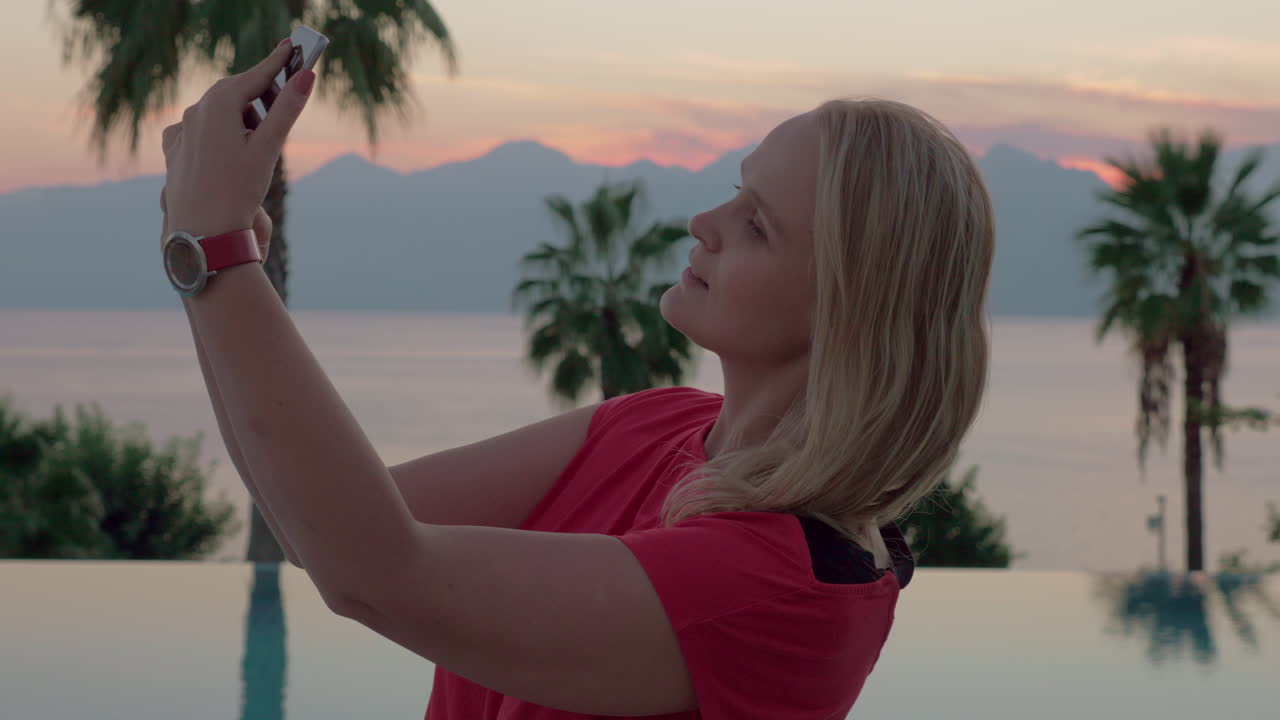 una mujer joven tomando selfies por el hermoso paisaje nocturno cerca de la piscina