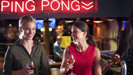 three female friends climbing stairs as they meet for drinks and socialize in bar