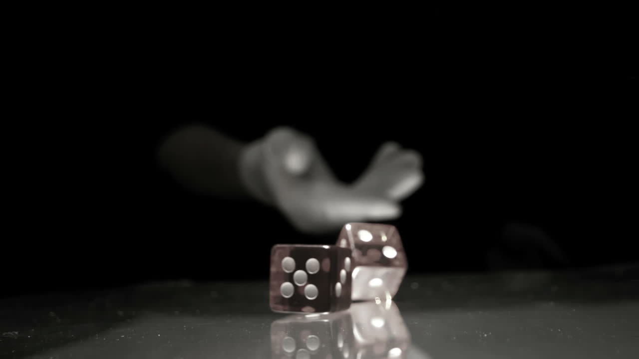 mano lanzando dos dados sobre la mesa en blanco y negro