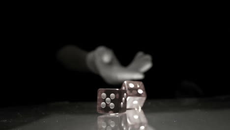 Hand-throwing-two-dice-onto-table-in-black-and-white