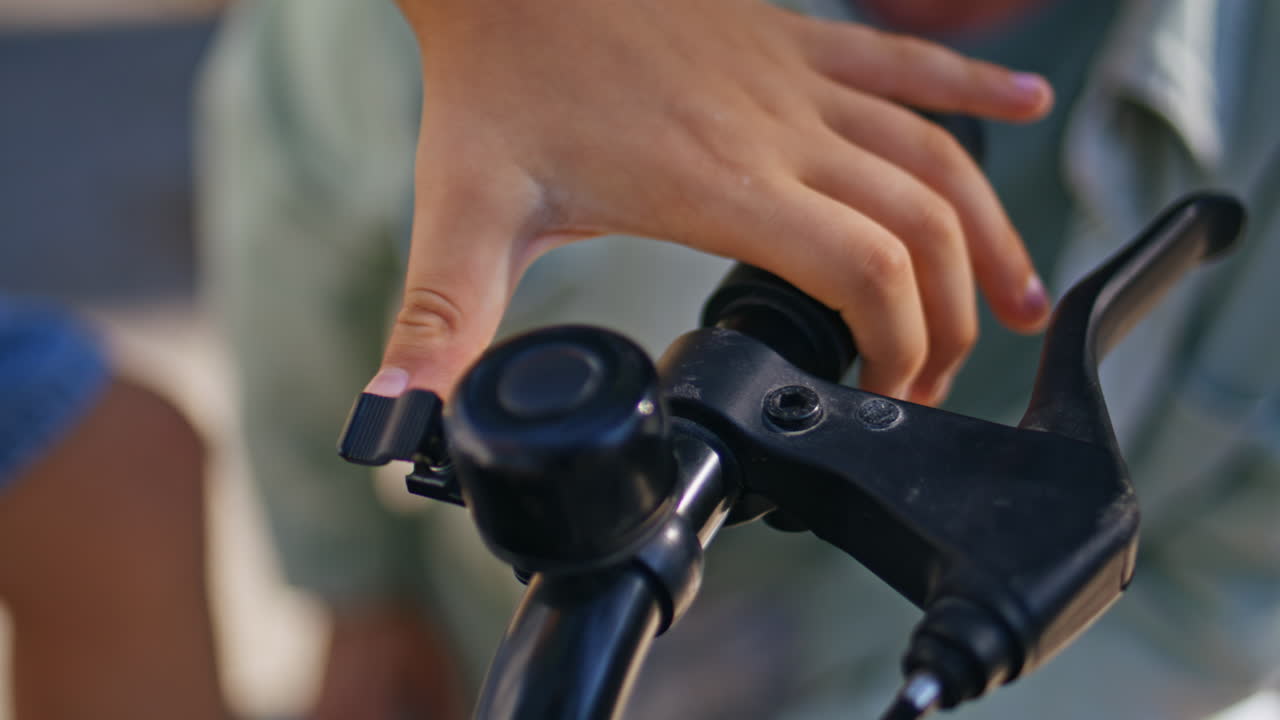 Kid hands touching bicycle outdoors closeup. Small boy preparing to bike ride