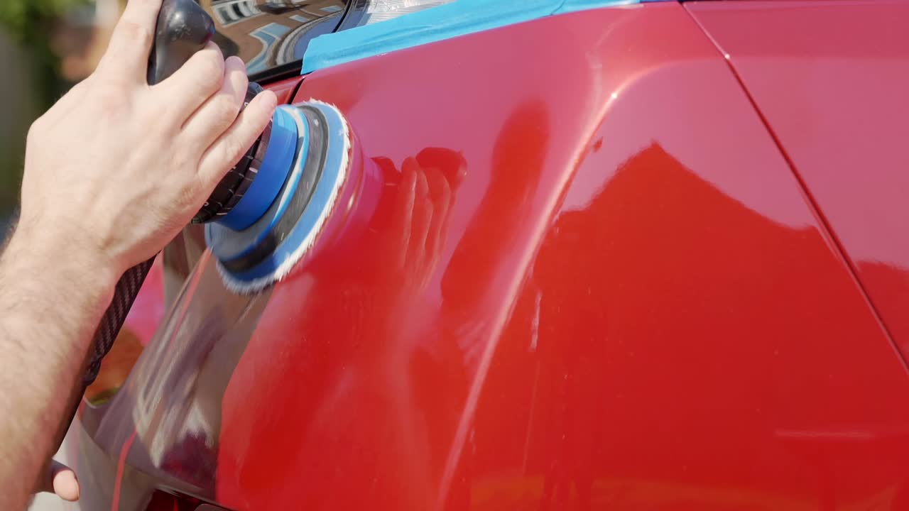 Nahaufnahme: Polieren der Kofferraumklappe eines roten Autos mit einer Poliermaschine mit Dual-Action