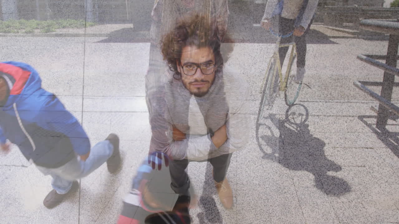 Crouching on sidewalk, man with glasses near bicycle and cyclist passing