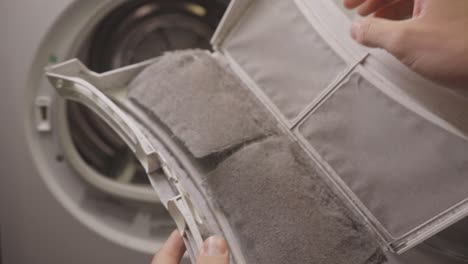 person cleans removable filter of a front load laundry machine