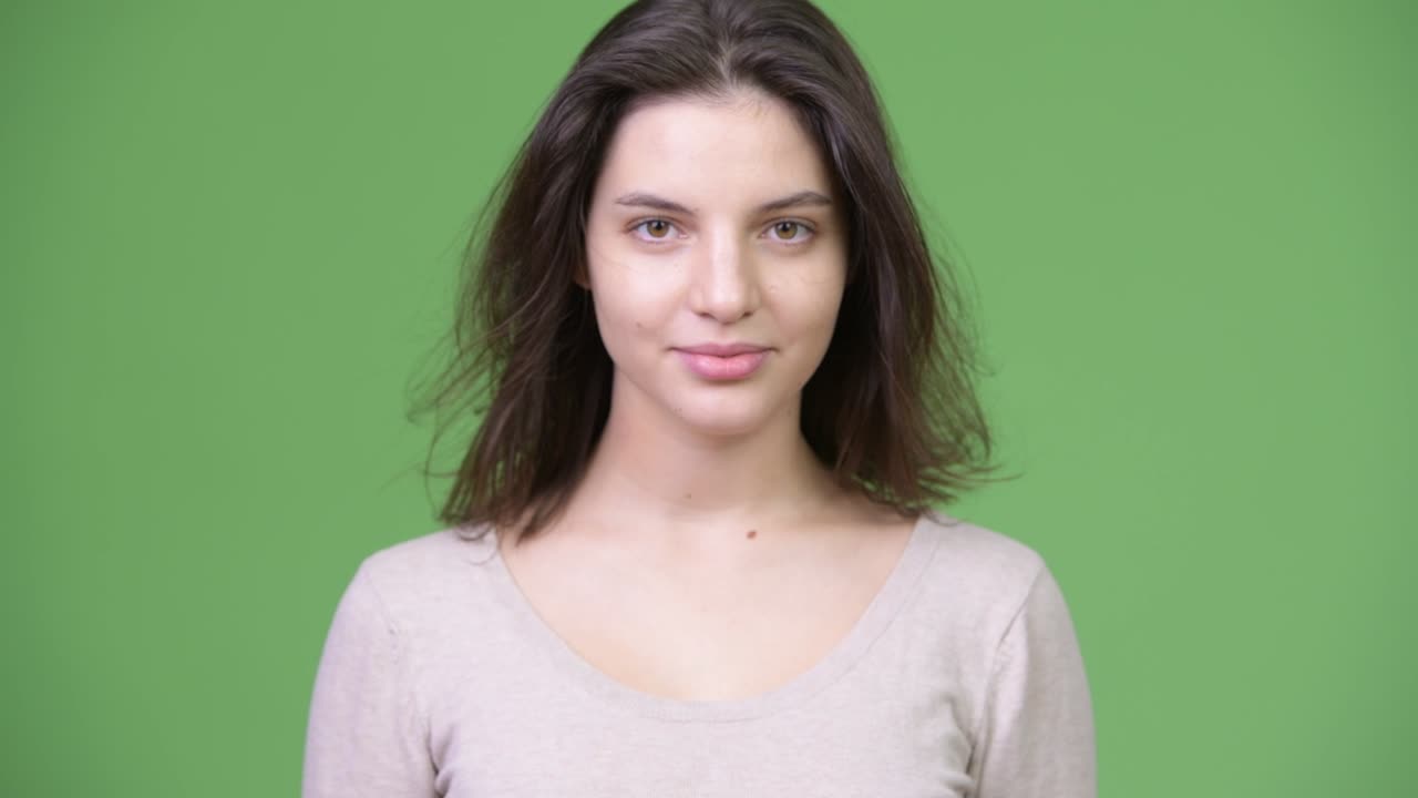 Giovane bella donna che si scuote i capelli su sfondo verde