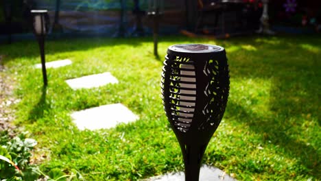 solar powered stylish modern torch lighting on sunlit garden lawn grass